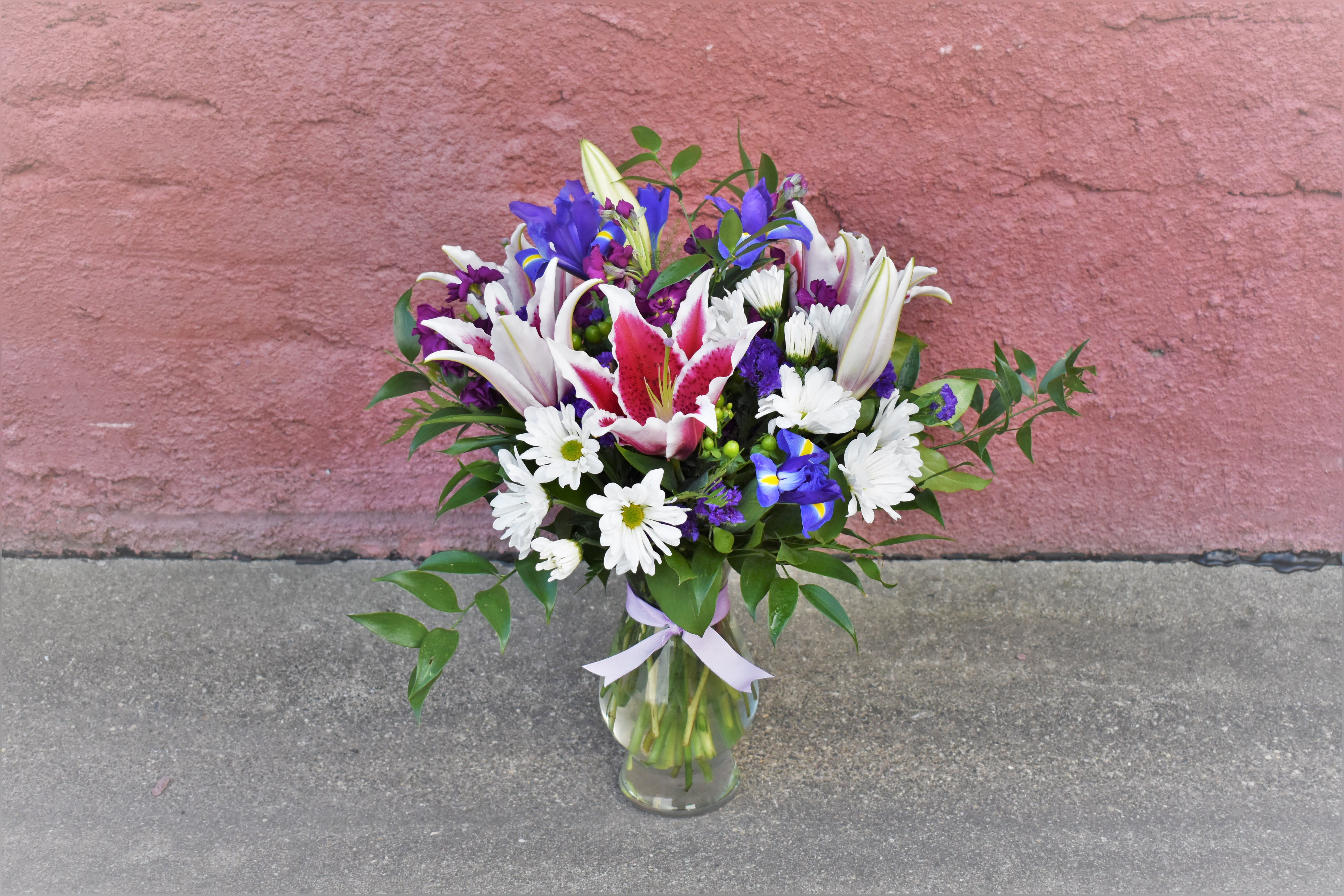 Bouquet of lilies, irises, and white daisies in a glass vase