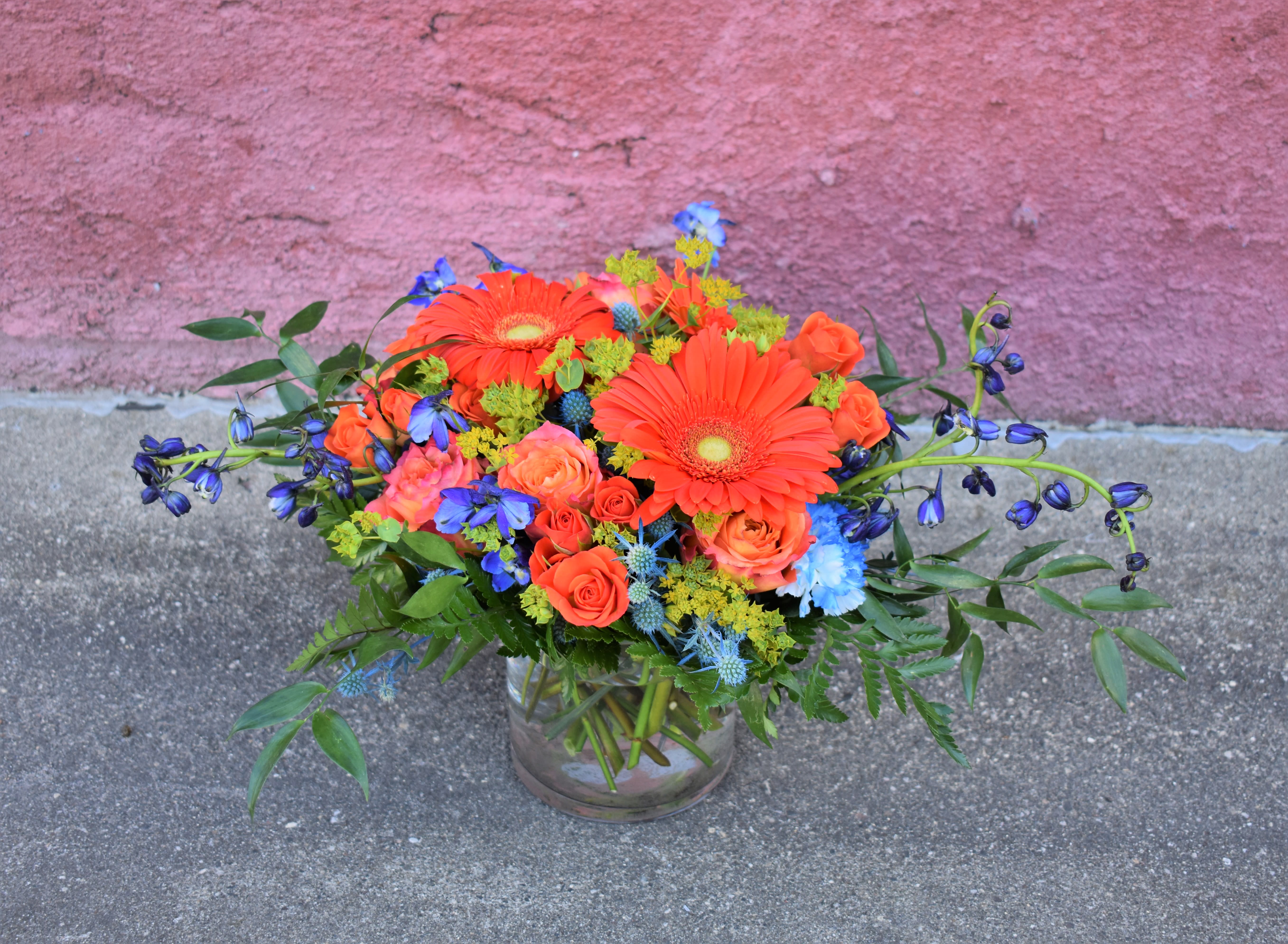 Bright mixed bouquet in a glass vase with orange and blue flowers