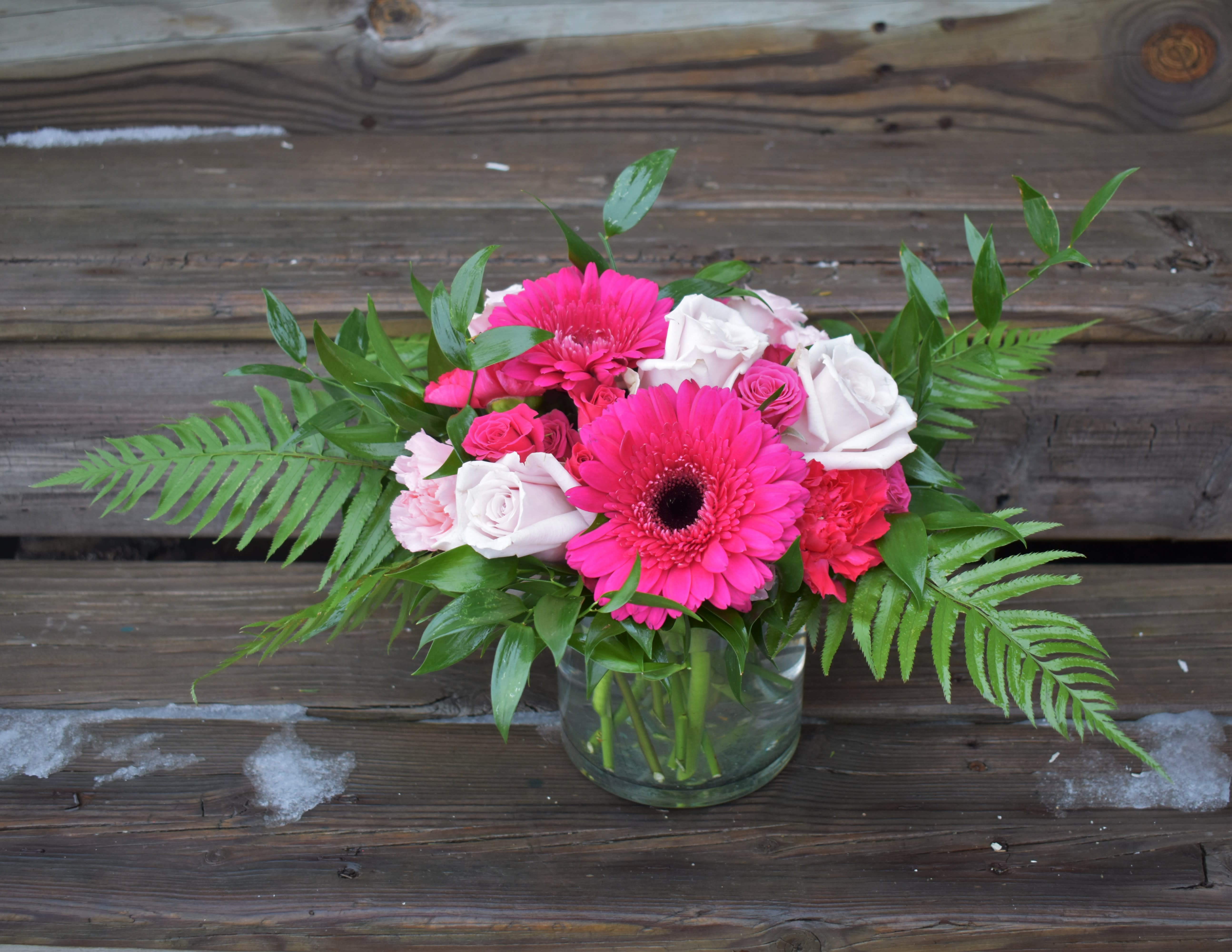 Pink gerbera daisies and roses in a glass vase