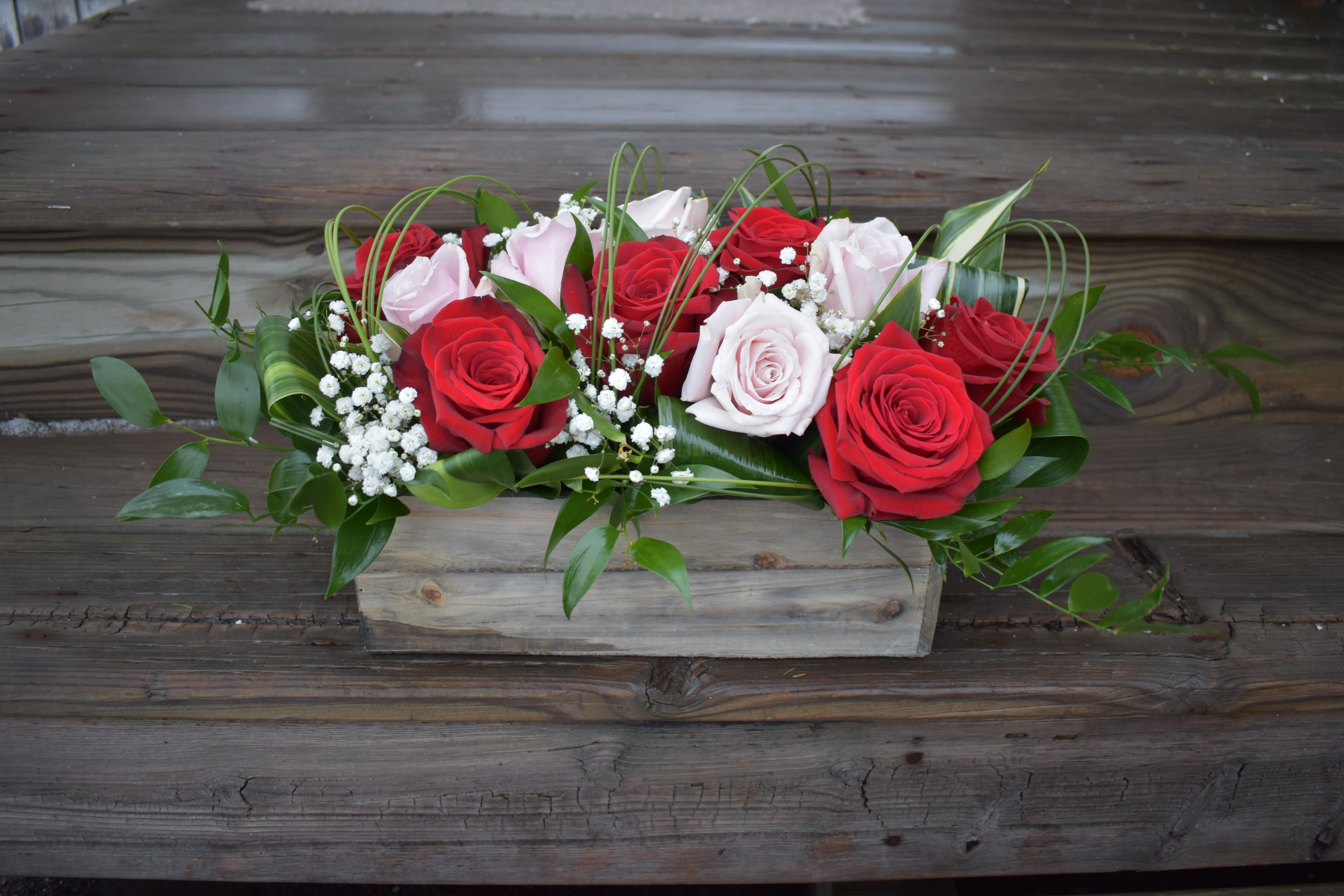 Red and pale pink roses arranged in a wooden box