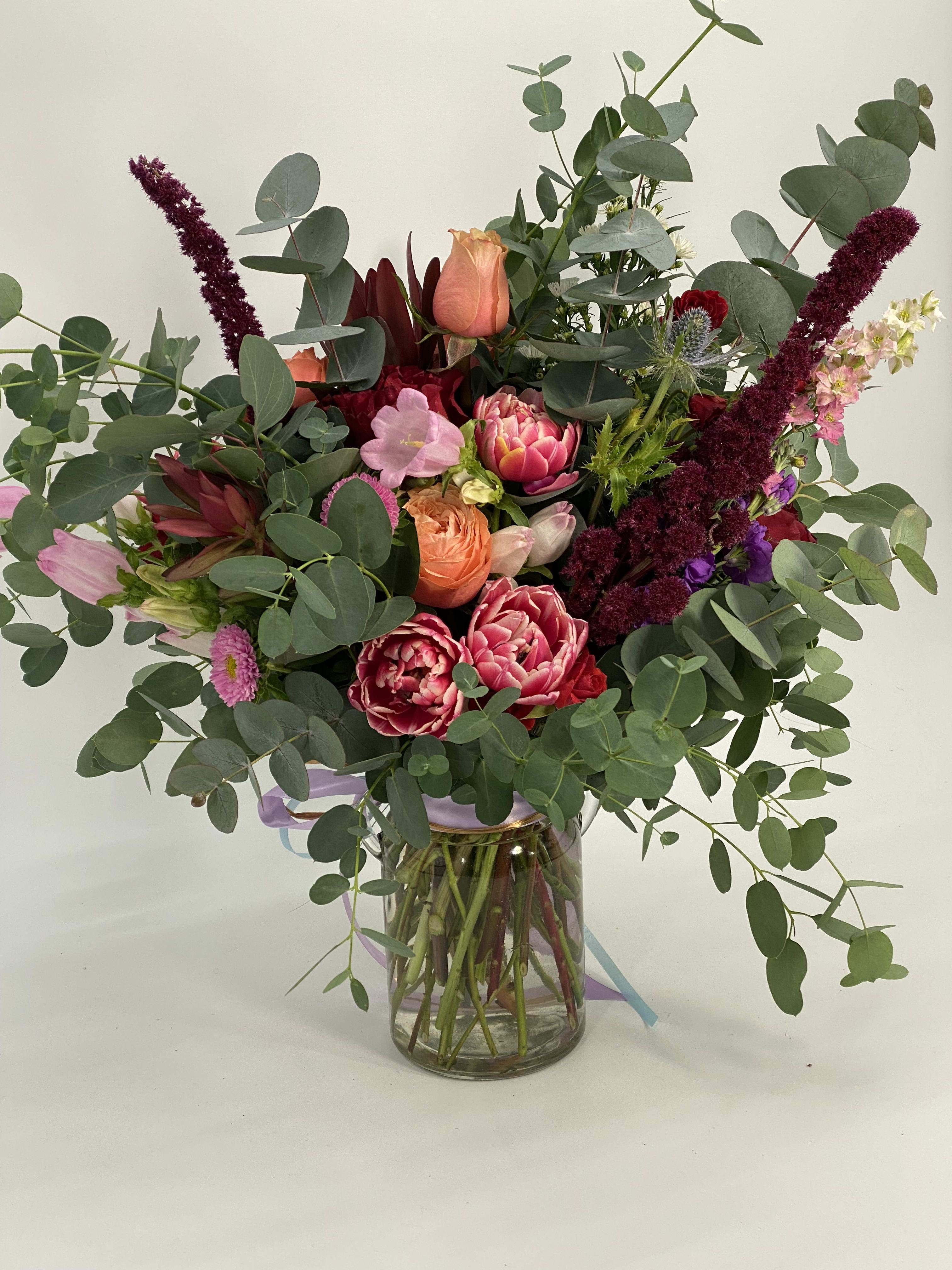 Mixed bouquet of pink and peach flowers in a glass vase