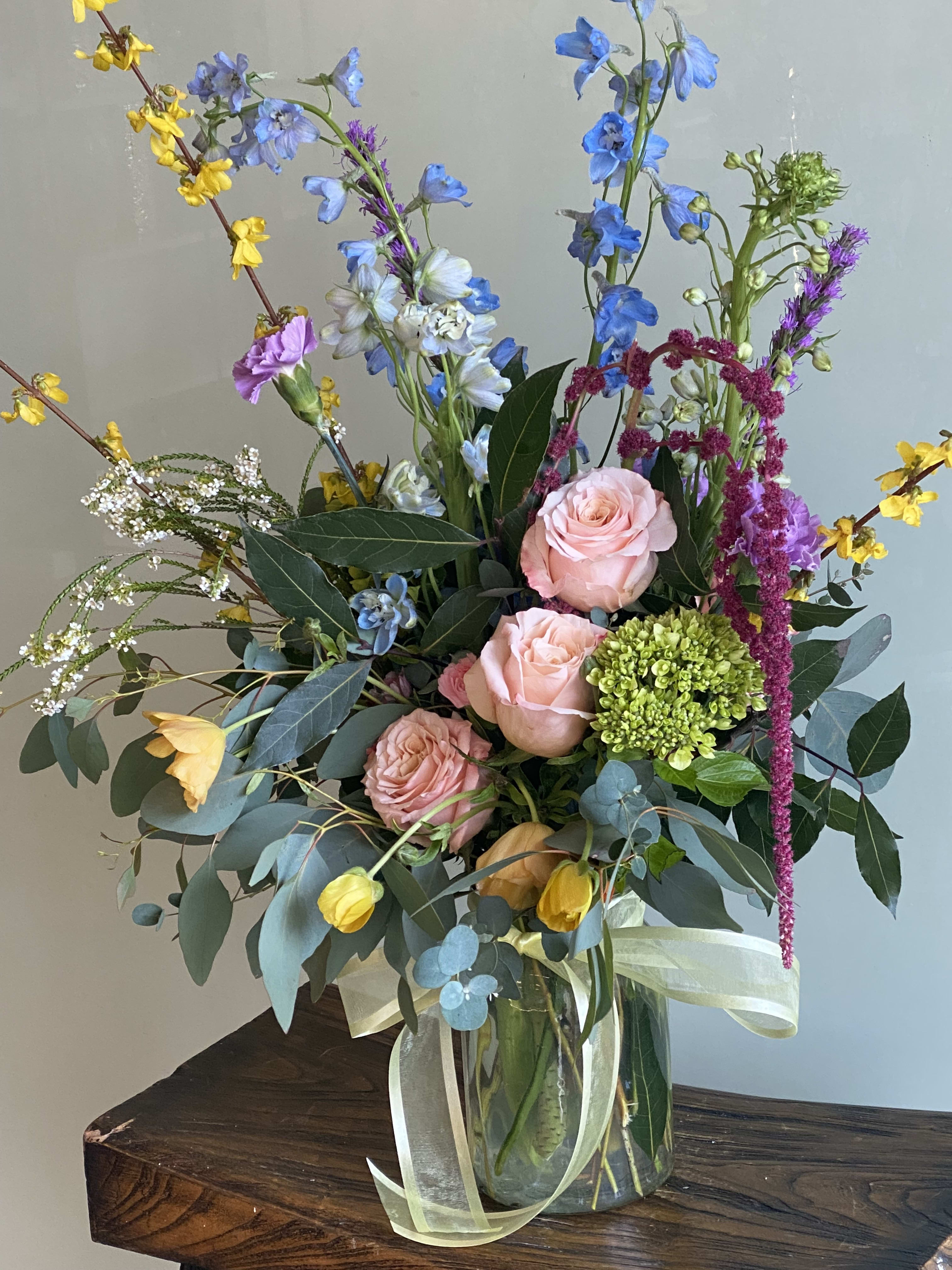 Tall mixed bouquet in a glass vase with pink roses and blue flowers