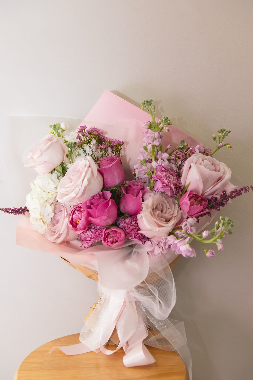 Pink and white mixed bouquet wrapped in translucent paper with a ribbon