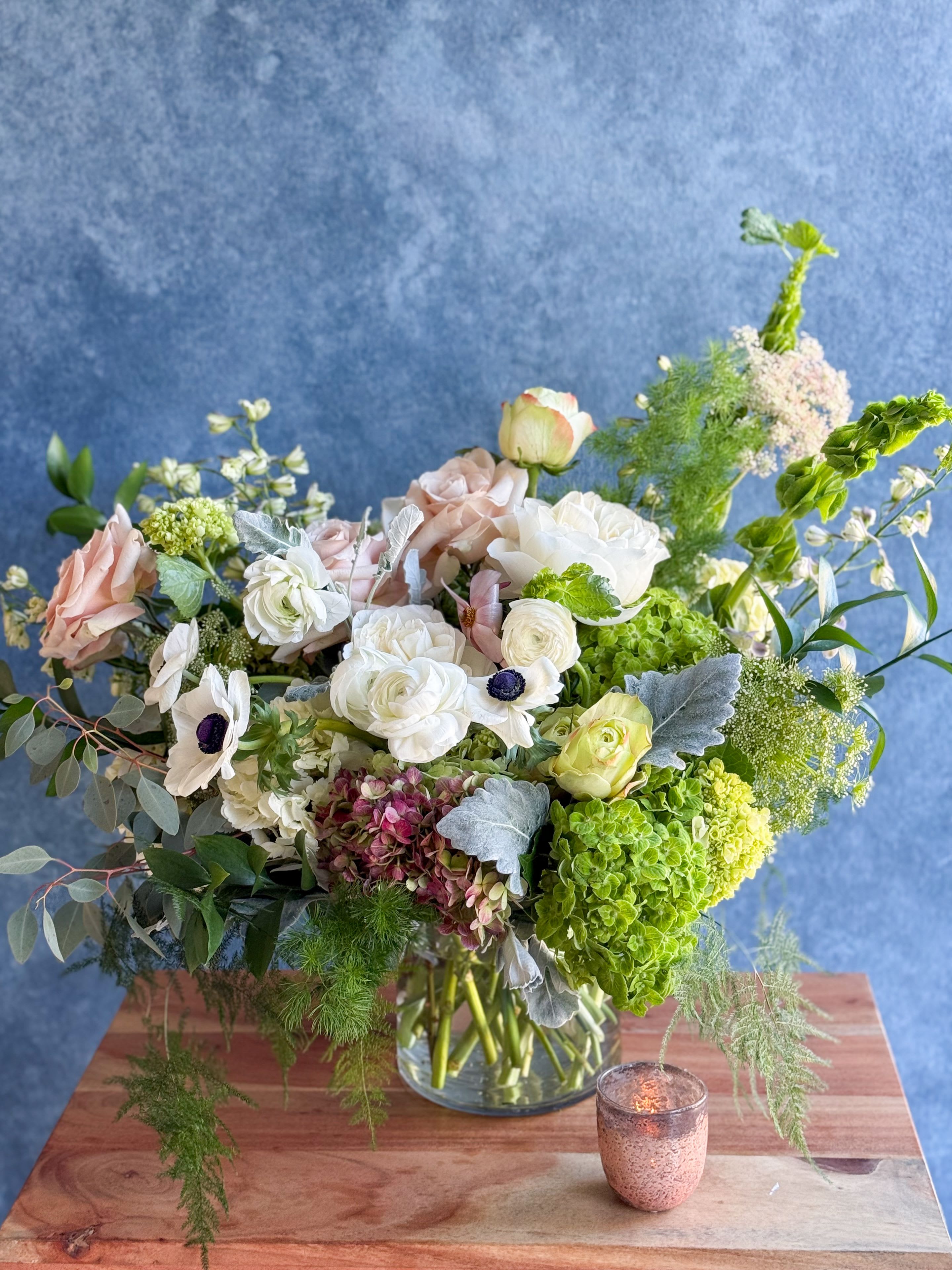 Mixed pastel bouquet in a glass vase with white, pink, and green blooms