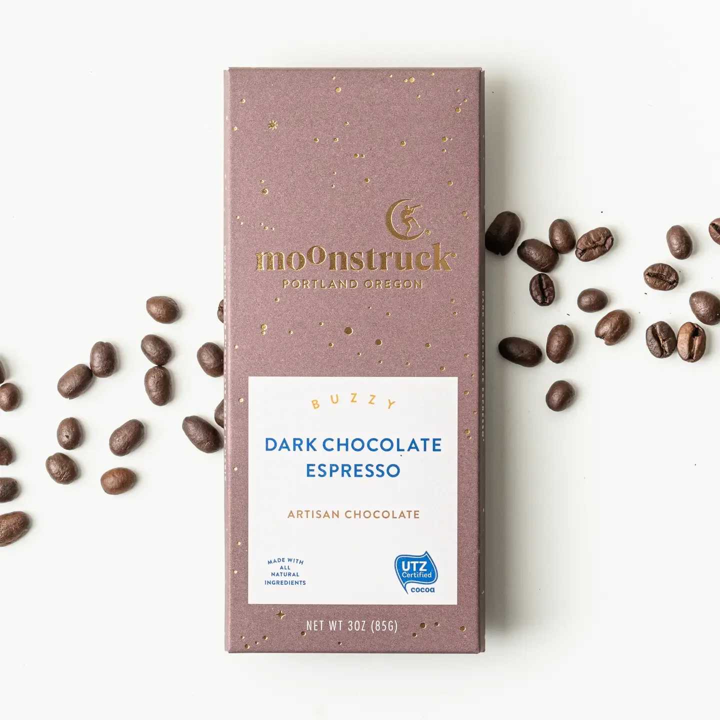 Box of dark chocolate espresso with coffee beans scattered around it