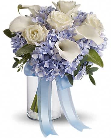 White calla lilies and roses in a glass vase with a blue ribbon