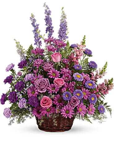 Purple and pink mixed flower arrangement in a wicker basket