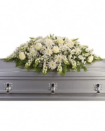 White floral casket spray on a gray casket