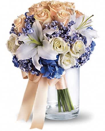 Bouquet of cream roses and white lilies with blue flowers in a glass vase