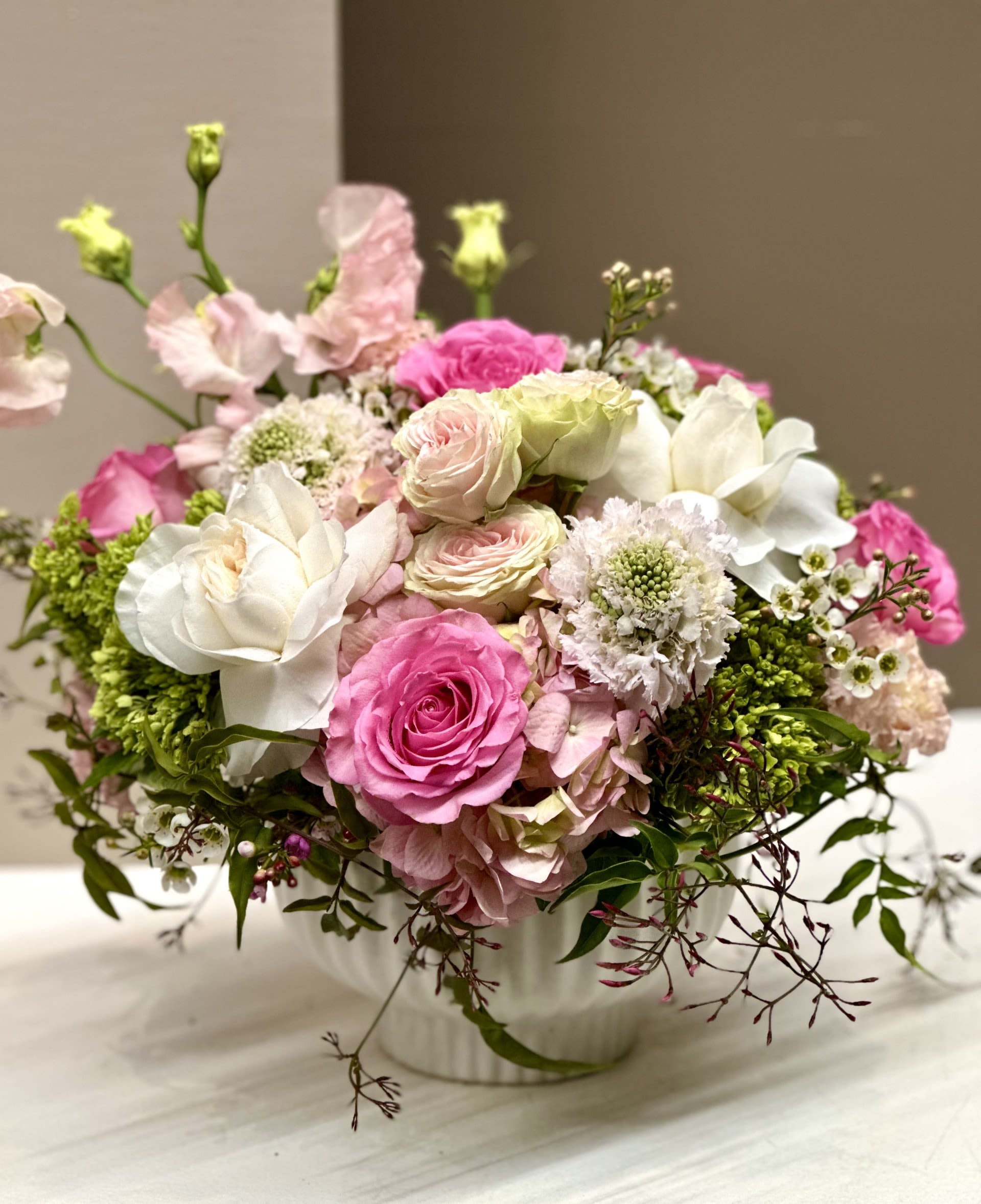 Pink and white roses arranged in a white vase
