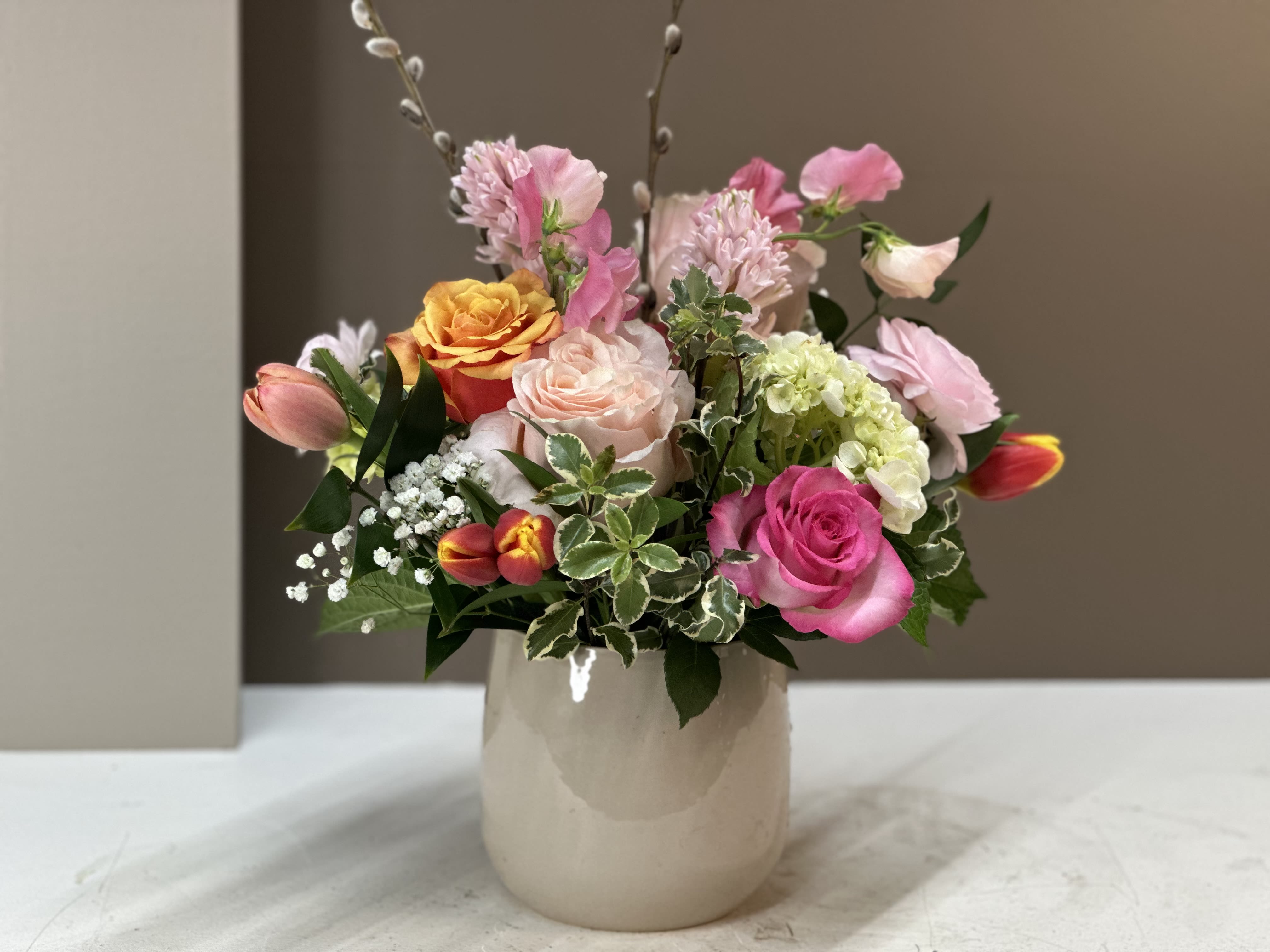 Spring Sorbet - A cheerful, garden-inspired arrangement bursting with Pinks, Coral, and Cream. Featuring Roses, Tulips, Sweet Peas, Hyacinth, Hydrangea, and delicate accent flowers, this design is artfully gathered in a keepsake vase for a fresh look.