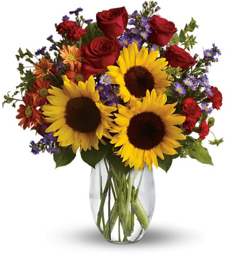 Bouquet of sunflowers, red roses, and purple daisies in a clear glass vase