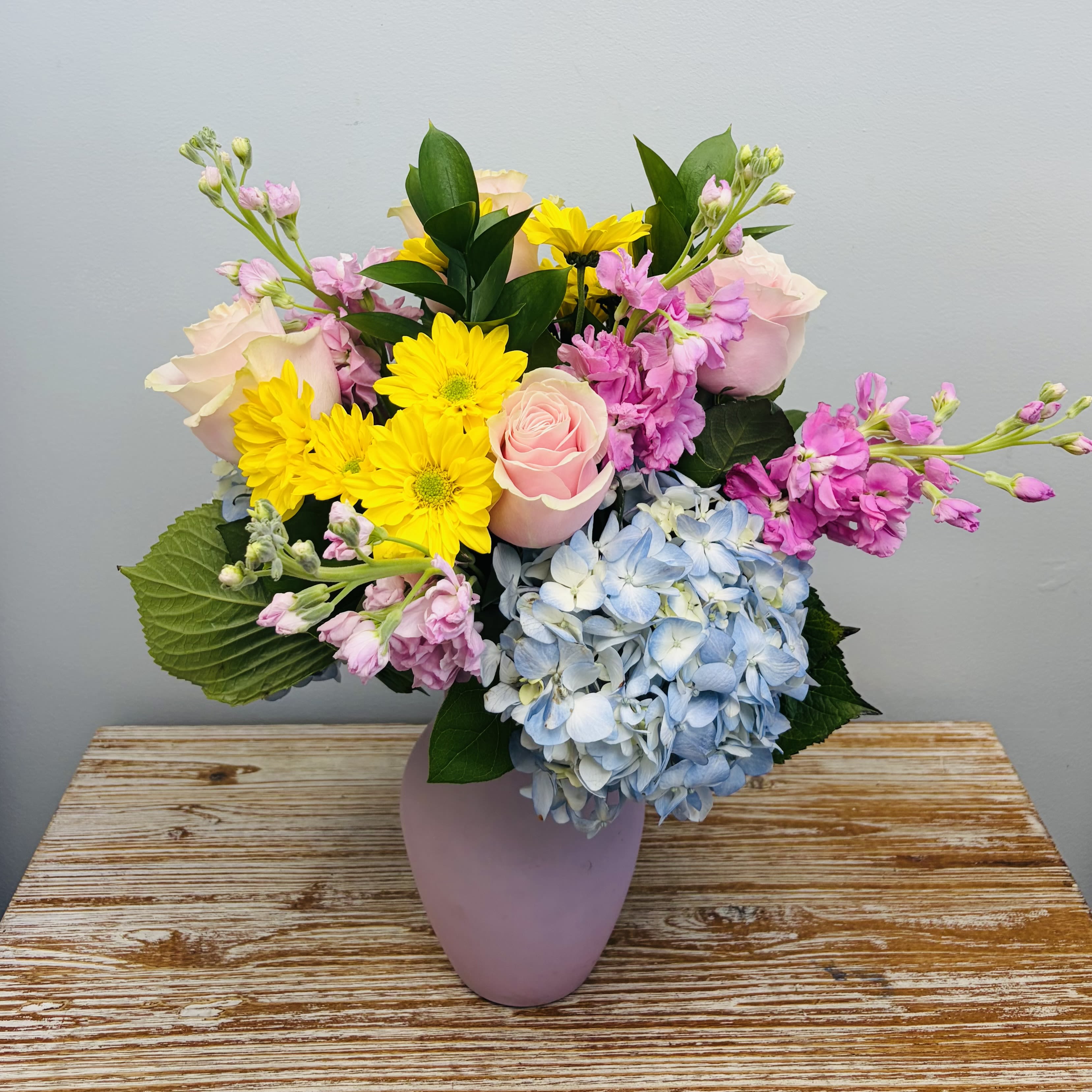Sweetheart - A colorful assortment of blooms of roses, hydrangeas, stock, and daisies in a pink vase.  Approximately 16-18” Tall 