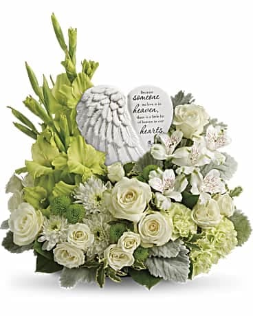 White and green sympathy arrangement with roses and gladiolus around an angel wing keepsake.