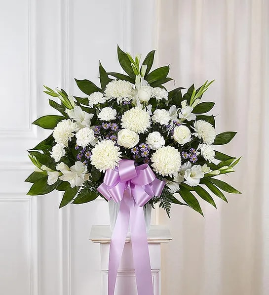White floral arrangement with a lavender ribbon in a vase