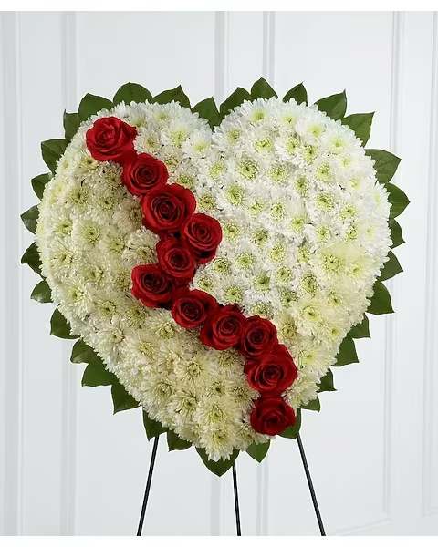 Heart-shaped white floral spray with red roses on a stand