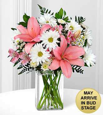 Pink lilies and white daisies arranged in a clear glass vase