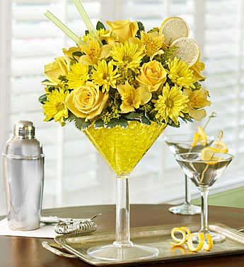 Yellow flower arrangement in a martini glass with lemon slices
