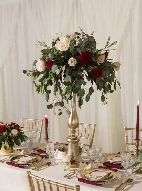 Tall floral centerpiece with red and white roses on a gold stand
