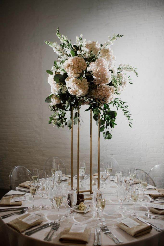 Tall floral centerpiece with blush and white blooms on a gold stand