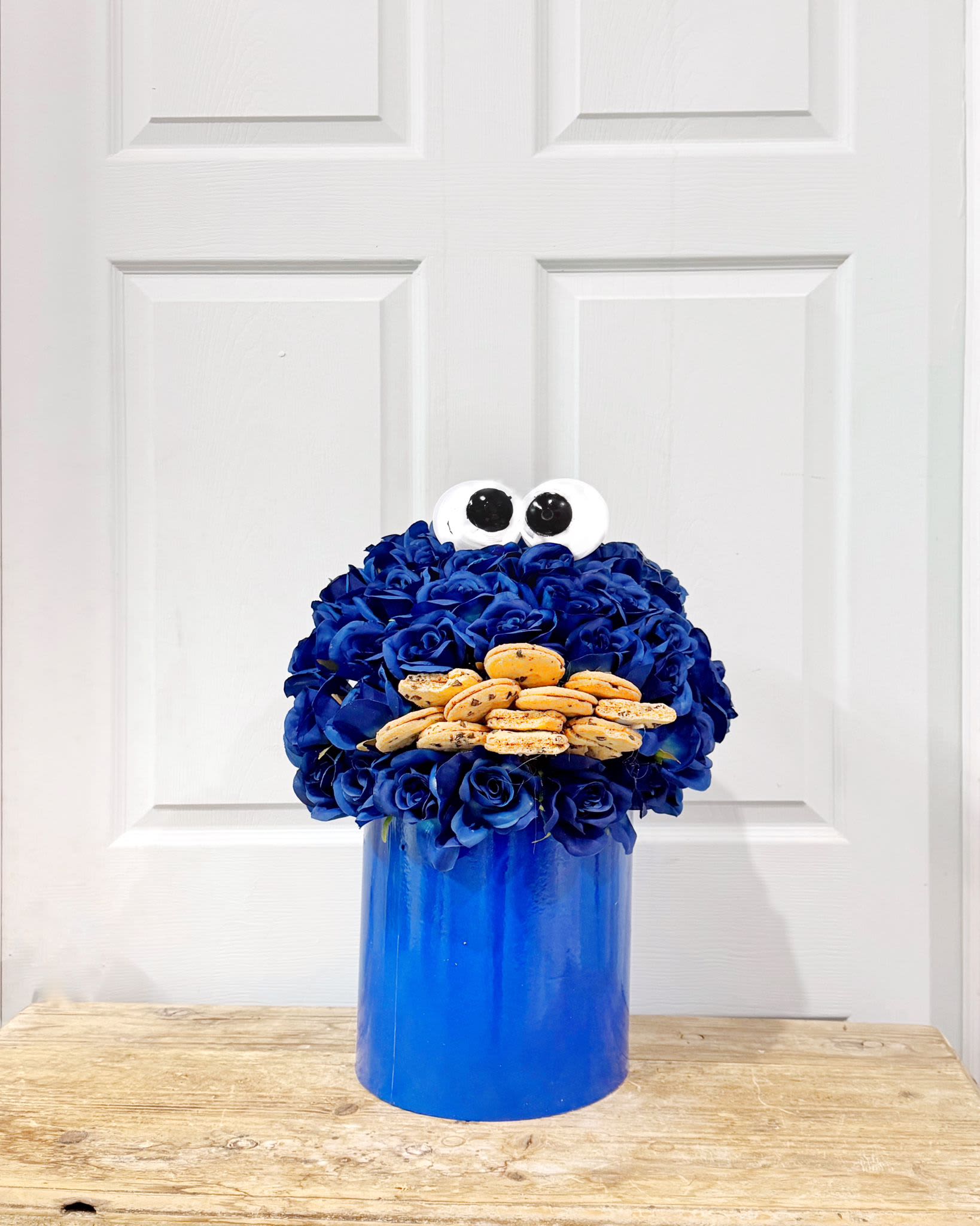 Blue flower arrangement with cookie eyes and a blue container