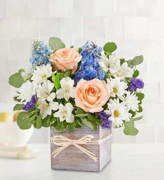 Peach roses and white daisies in a wooden box