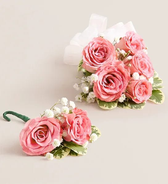 Two pink rose boutonnieres with white baby's breath and ribbon