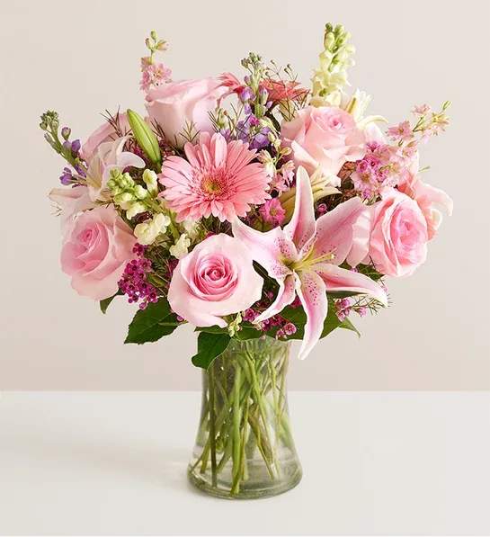 Pink roses and lilies arranged in a clear glass vase