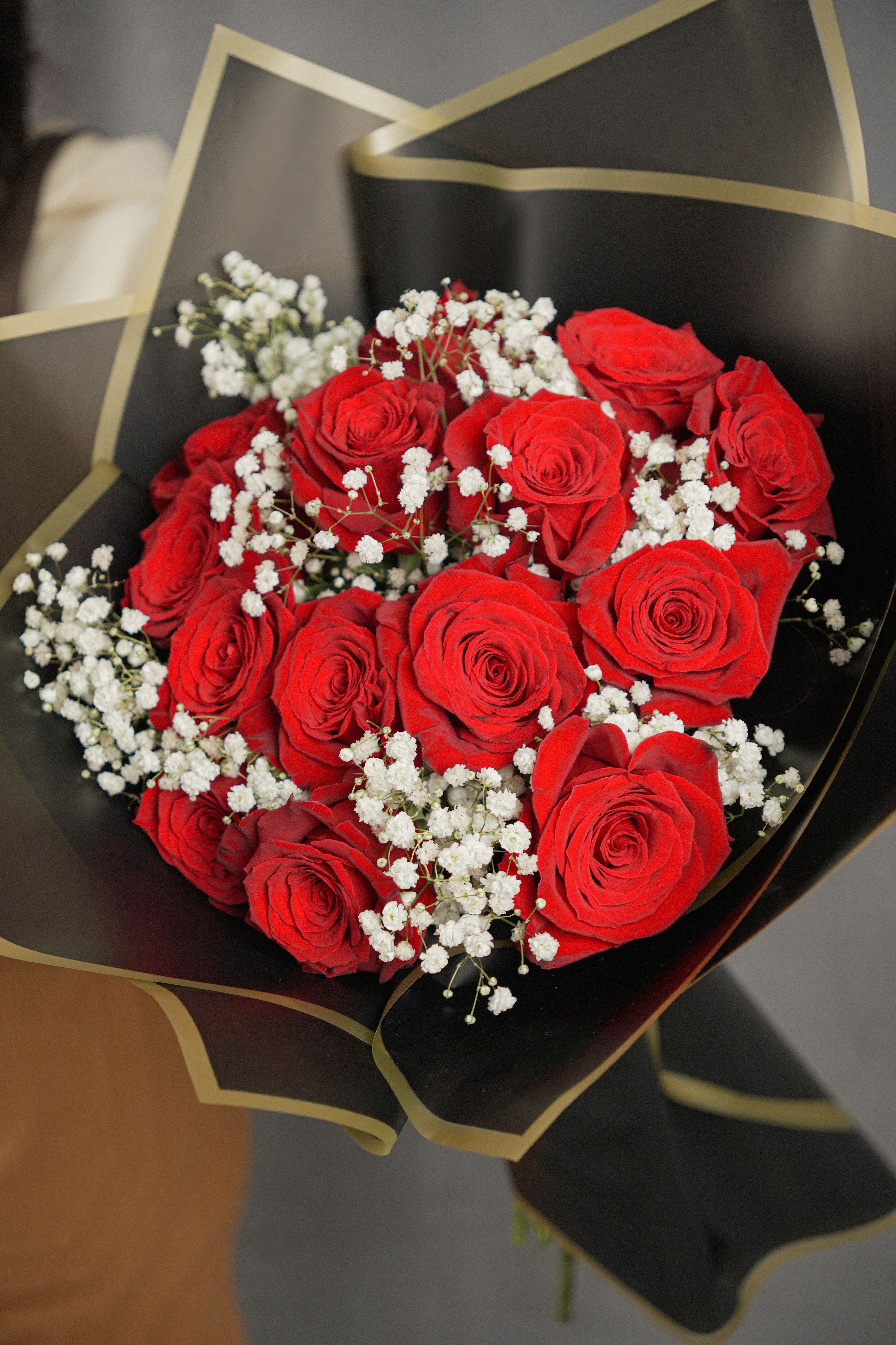 Bouquet of red roses with white baby's breath in black wrap