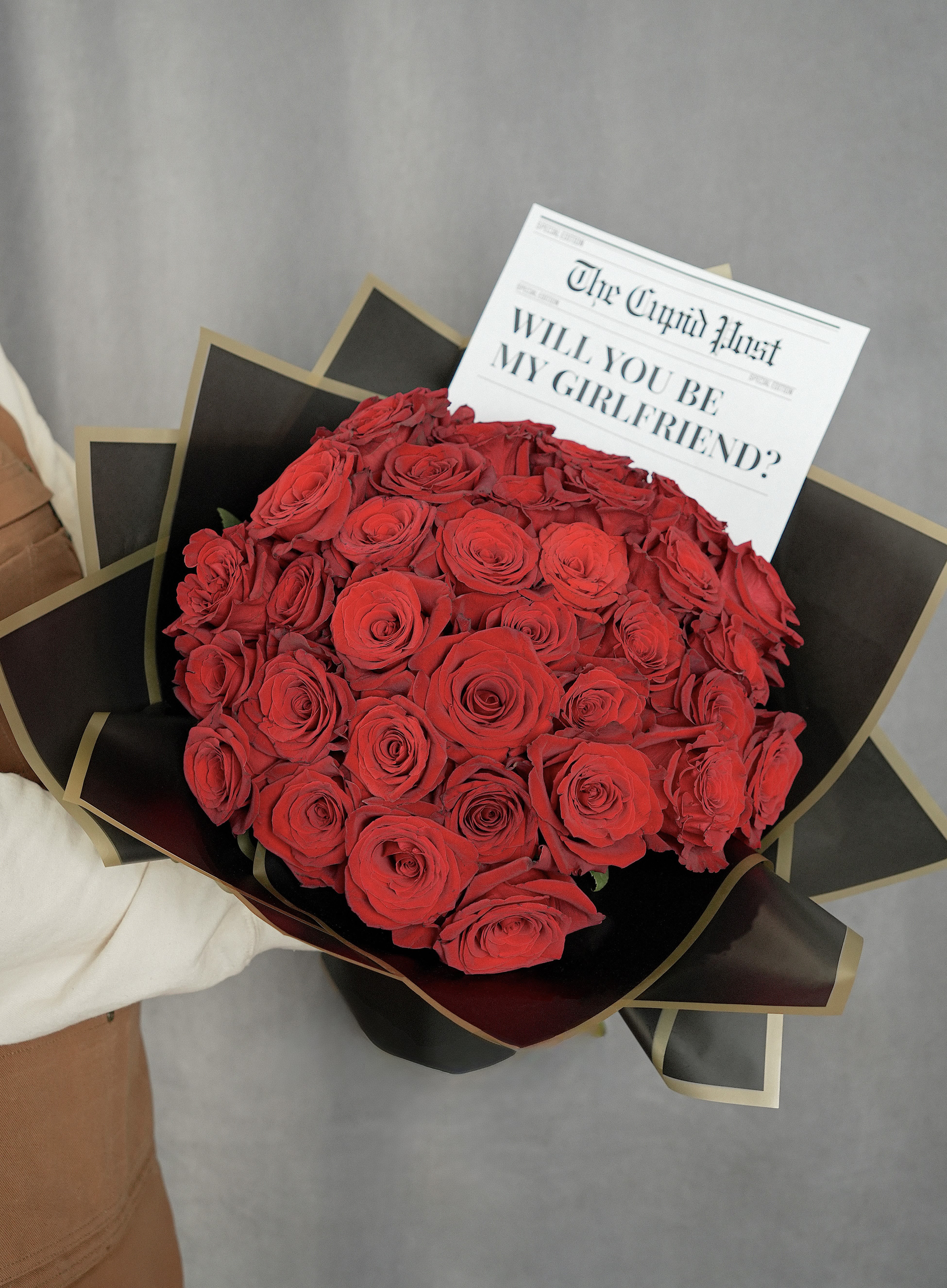 Bouquet of red roses wrapped in black paper with a printed card