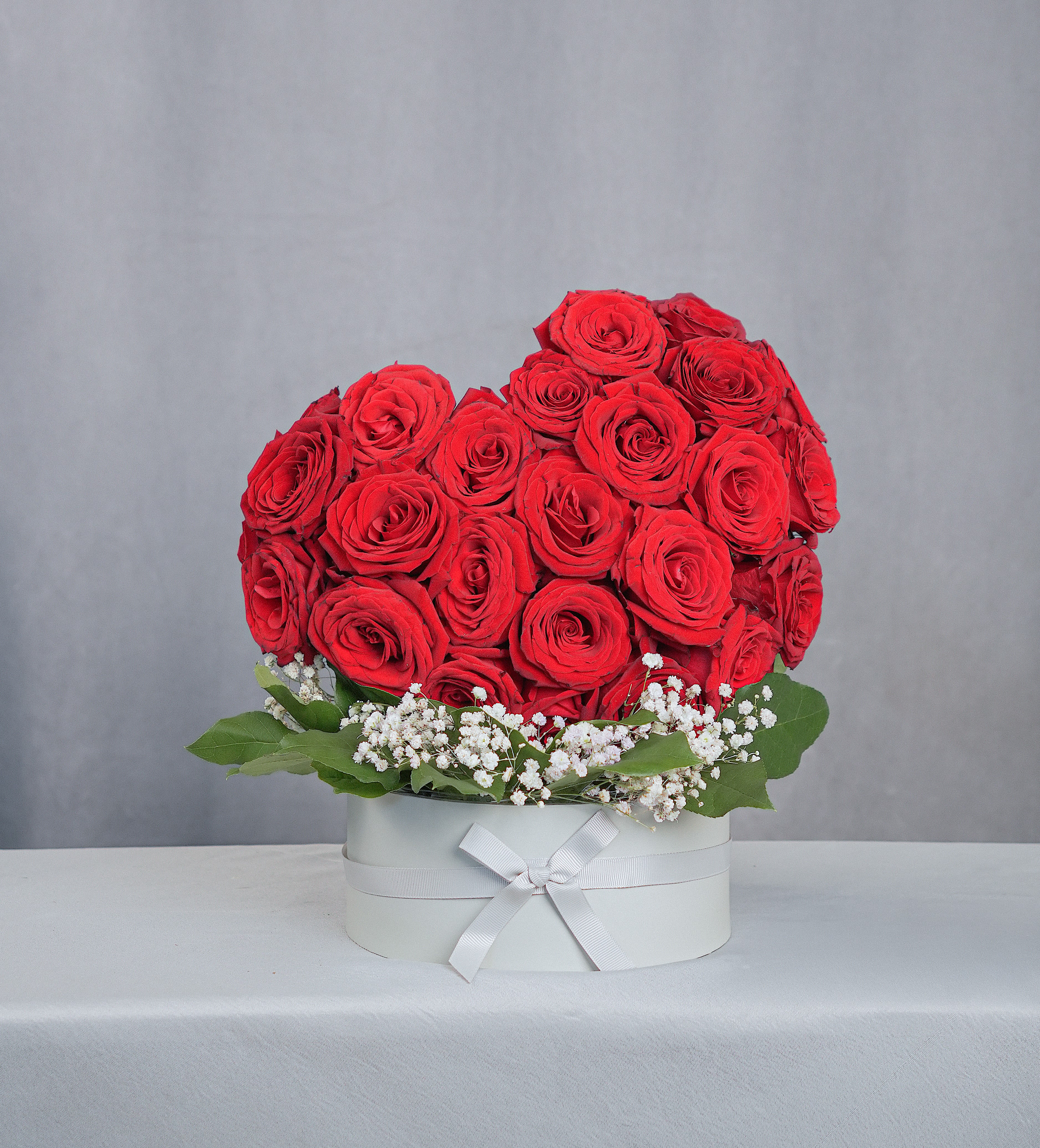 Red rose arrangement in a white round box with baby's breath