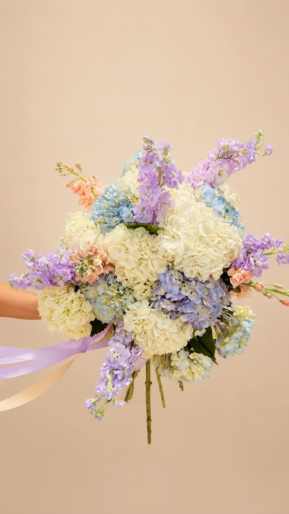 SUMMER IN PROVENCE  - Creamy white hydrangeas take center stage in this large hand-tied bouquet, their full clustered blooms softened by pale blue, lavender and blush pink accents for a springlike, romantic look - perfect as a wedding bouquet, birthday surprise, or celebratory gift. Tall stock stems and airy lavender spikes lift the arrangement, giving it a loose, garden-style silhouette that feels both abundant and effortlessly elegant; the person you're thinking of will feel gently celebrated the moment they see it.