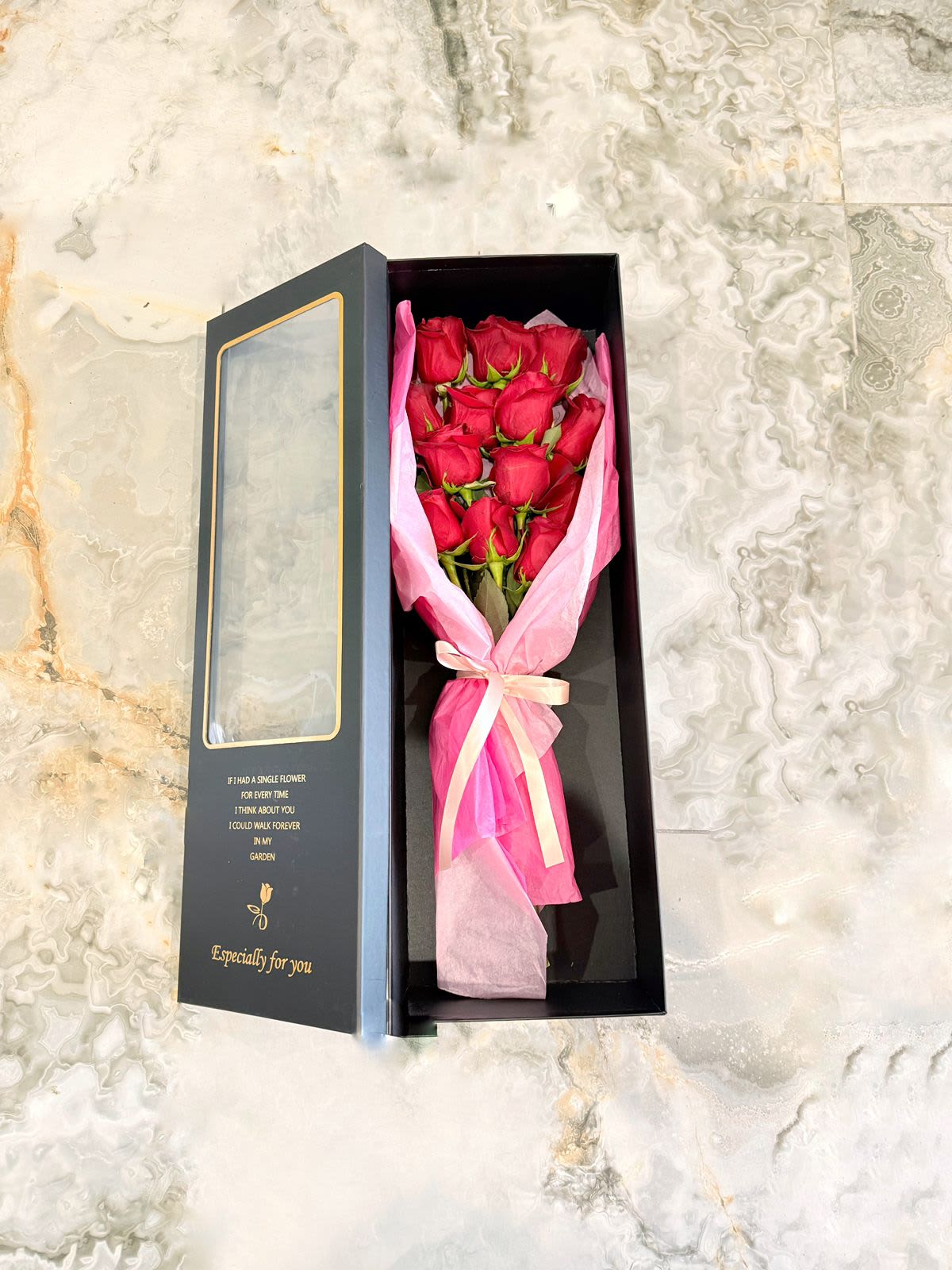 Boxed bouquet of red roses wrapped in pink tissue