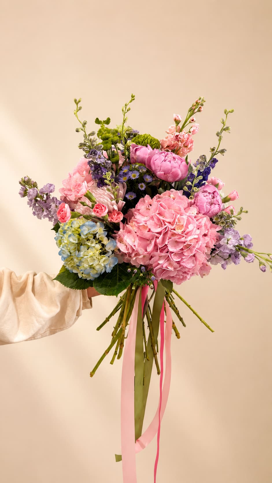 WILD GARDEN SYMPHONY - A lush, hand-tied garden bouquet that feels like a spring meadow gathered just for her - perfect as a birthday bouquet, anniversary flowers, or a Mother's Day gift. This large arrangement blends rounded pink peonies and full hydrangea heads with sprays of stock, carnations, chrysanthemums, daisies and aster-like fillers, creating a romantic, airy silhouette that reads both elegant and joyful for weddings or special celebrations. Some flowers may be substituted depending on the season. 