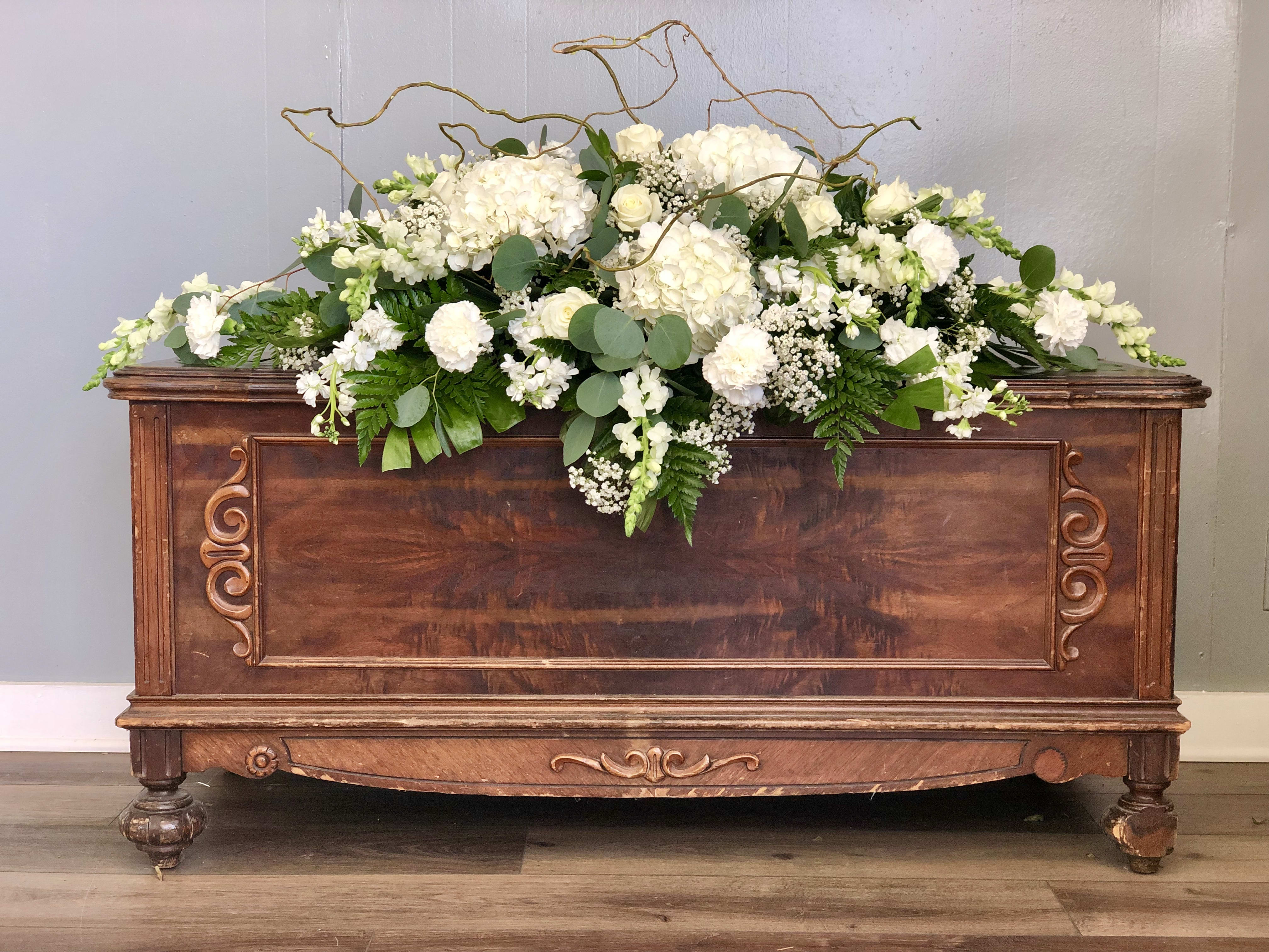 White floral arrangement on a wooden chest with curly branches