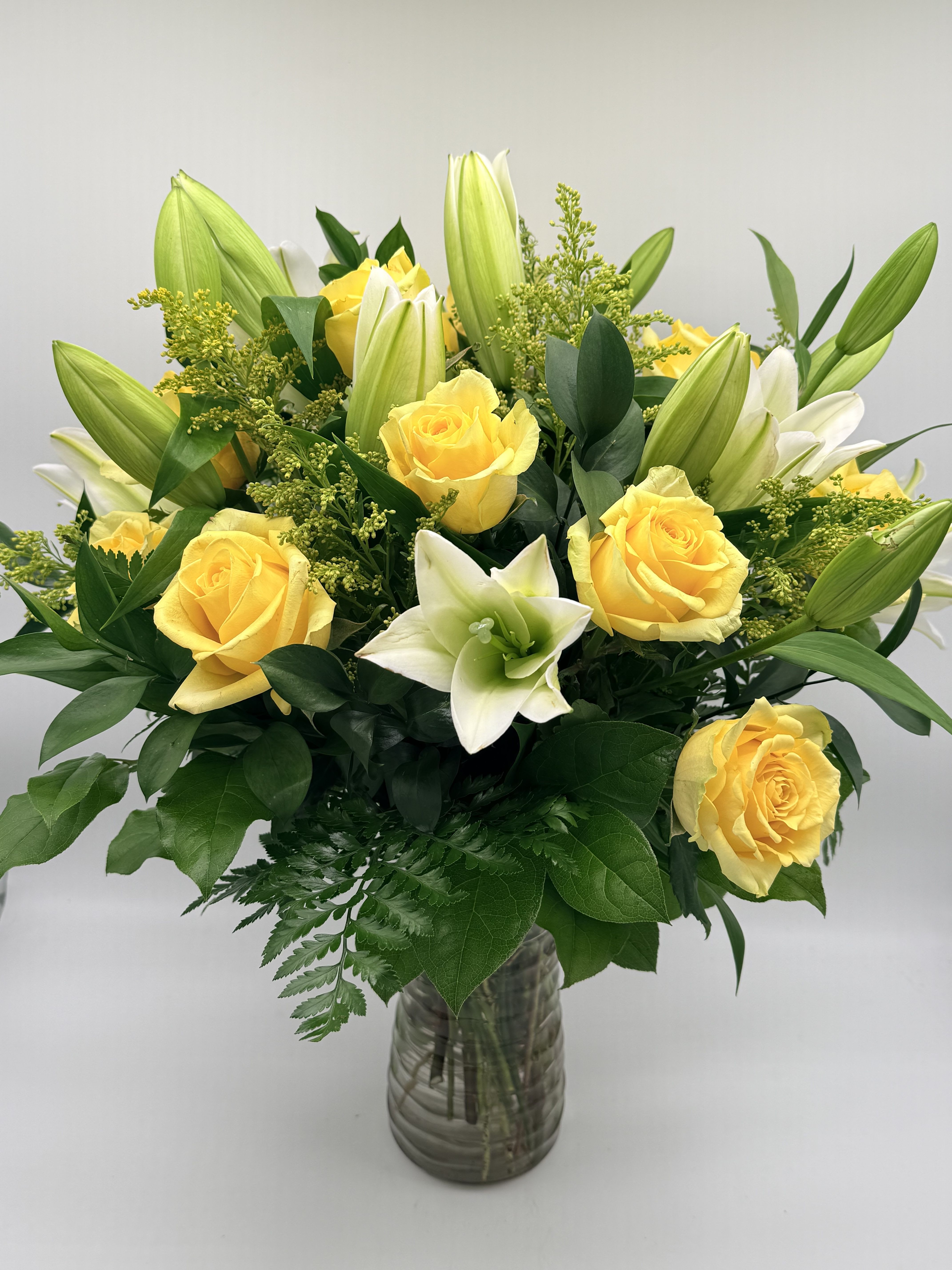 Yellow roses and white lilies in a glass vase