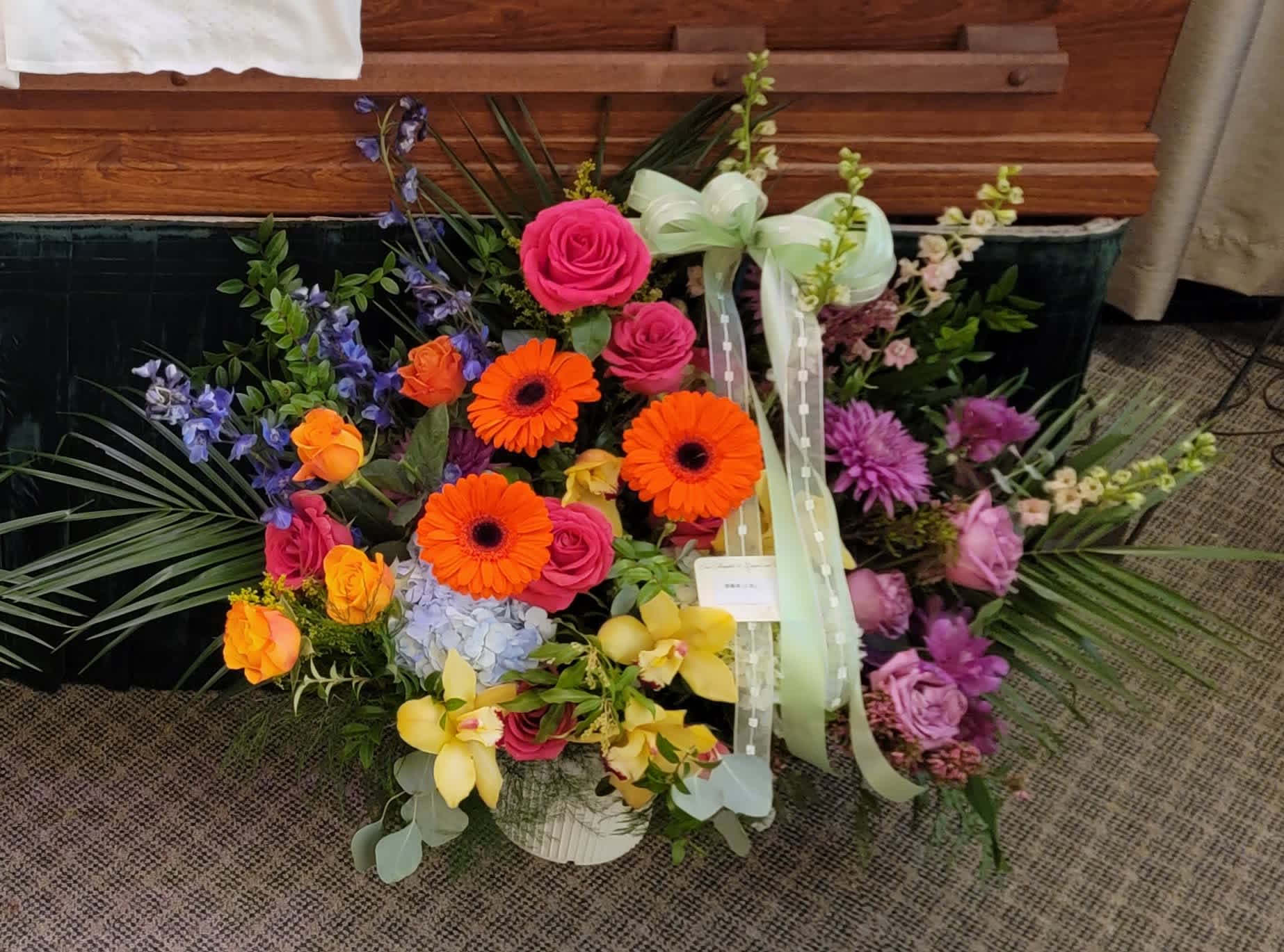 Colorful mixed flower arrangement with roses, gerberas, and orchids in a basket