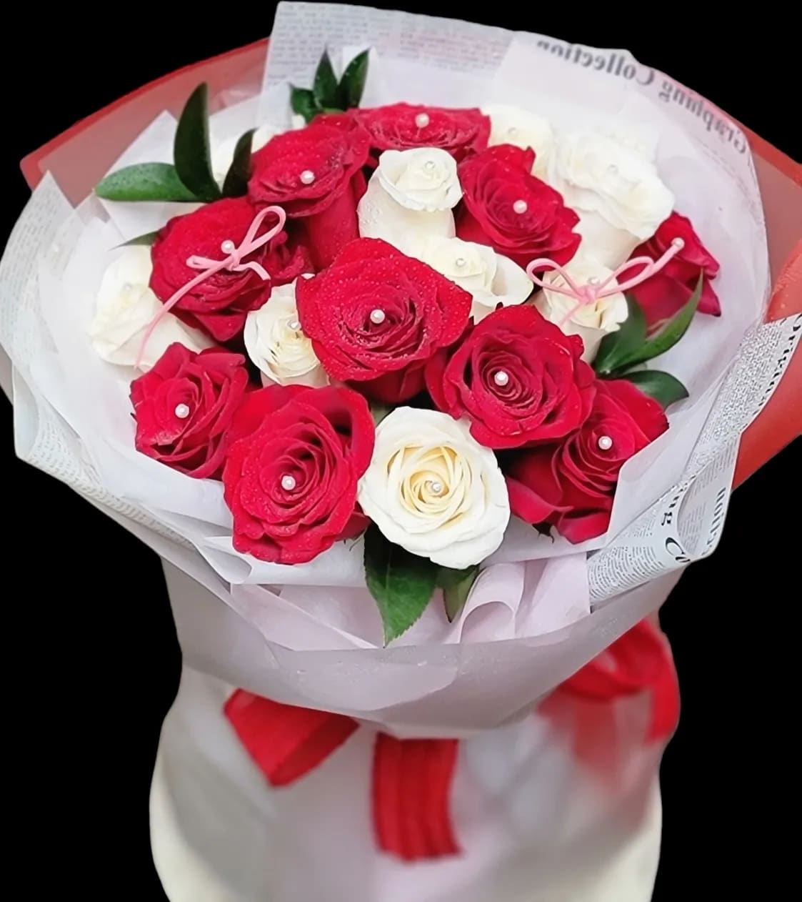 Bouquet of red and white roses wrapped in paper with a red ribbon