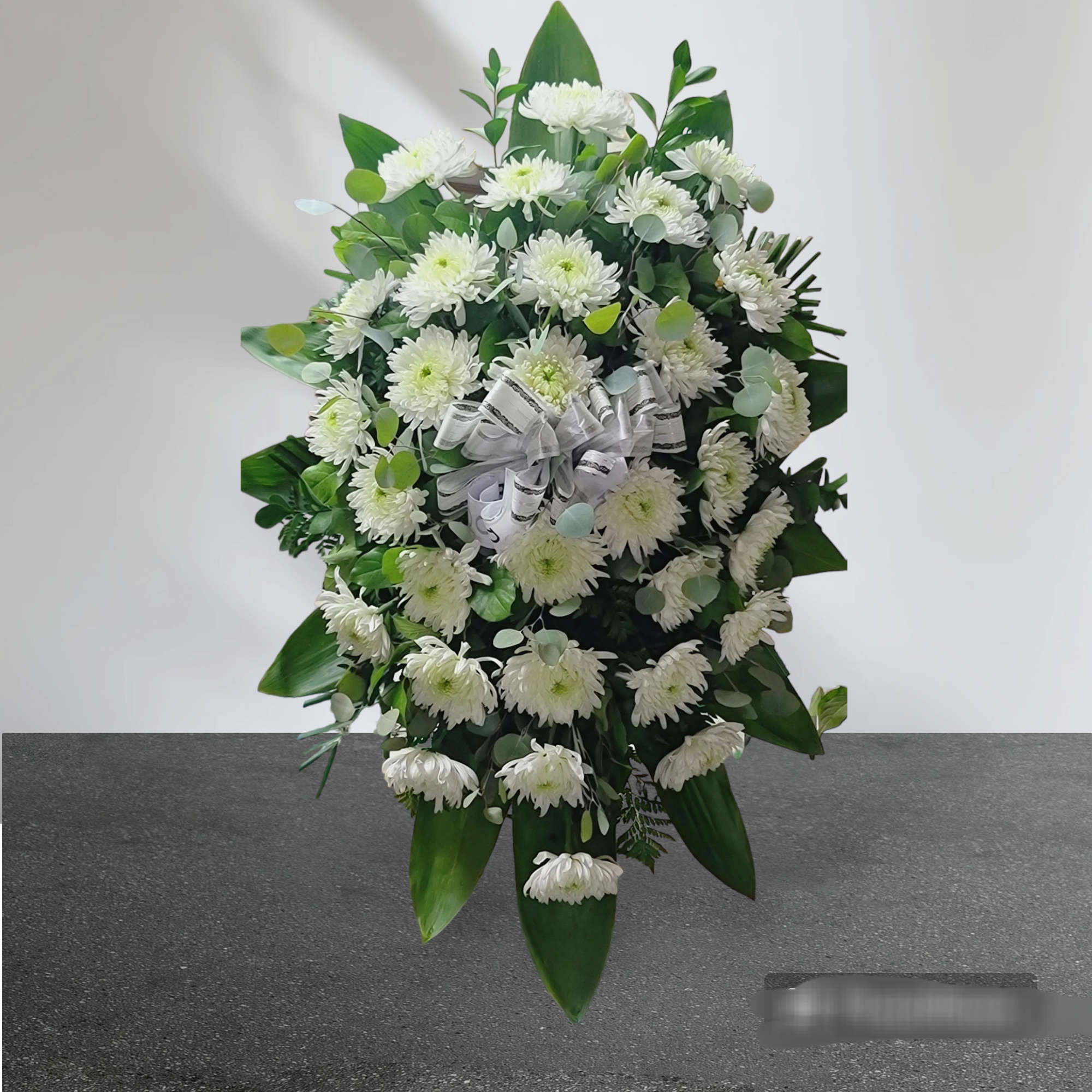 White chrysanthemum standing spray with a white ribbon bow