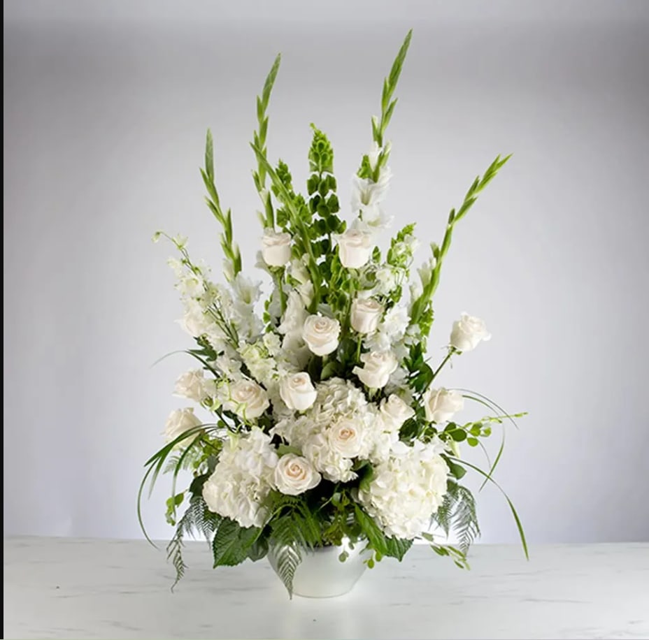 Tall white floral arrangement in a white bowl vase with roses and greenery