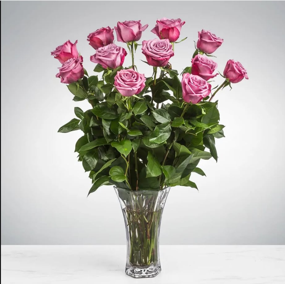 Dozen Long Stemmed Lavender Roses by BloomNation™ - This arrangement is the perfect "pick me up" to brighten someone's day. Dozen Long Stemmed Lavender Roses by BloomNation™ is the perfect gift for a birthday, get well, just because, and thank you.    Arrangement Details: 12 Long Stemmed Lavender Roses and Assorted Greenery APPROXIMATE DIMENSIONS: 25" H X 18" W
