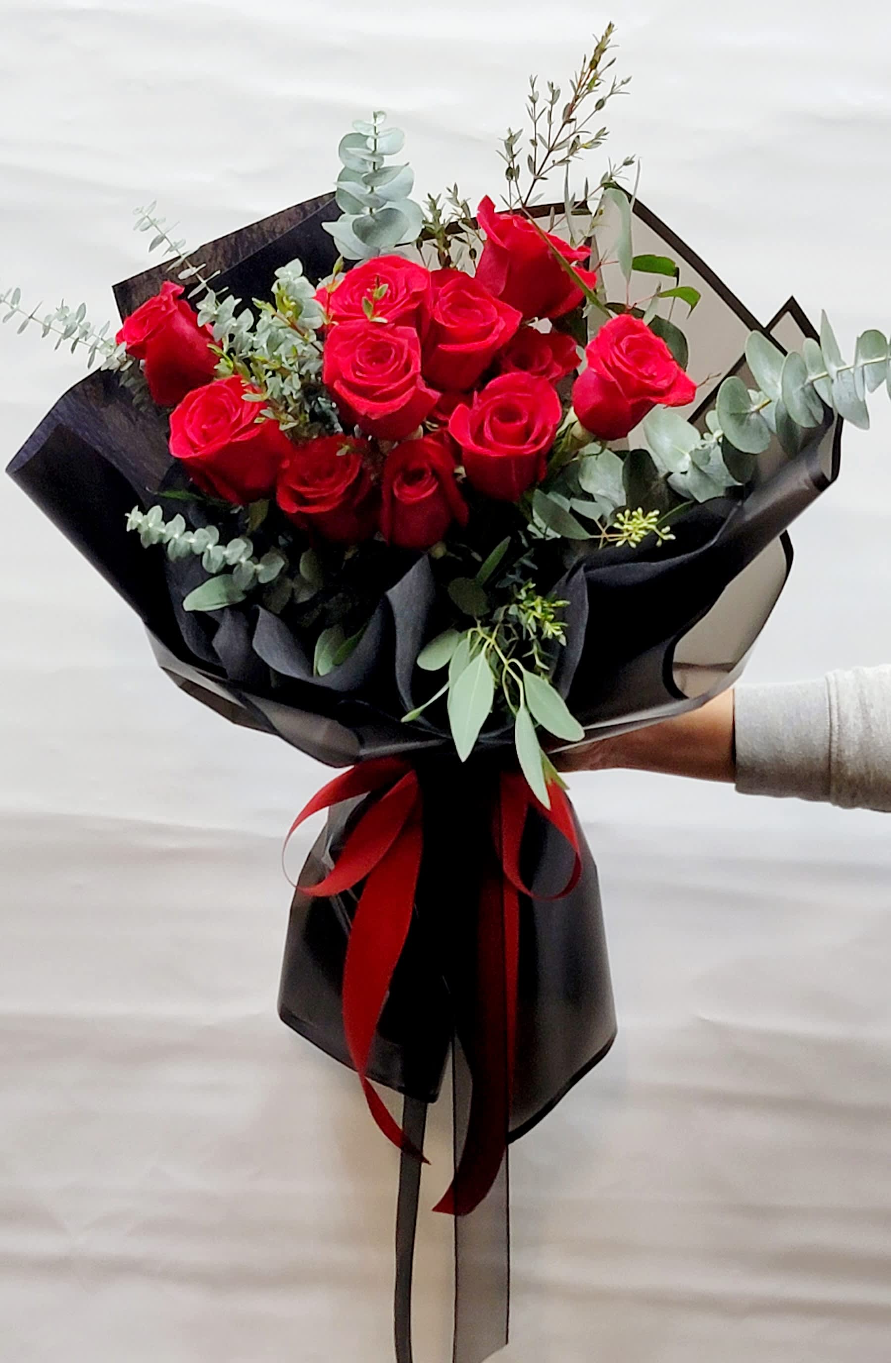 Bouquet of red roses wrapped in black paper with a red ribbon