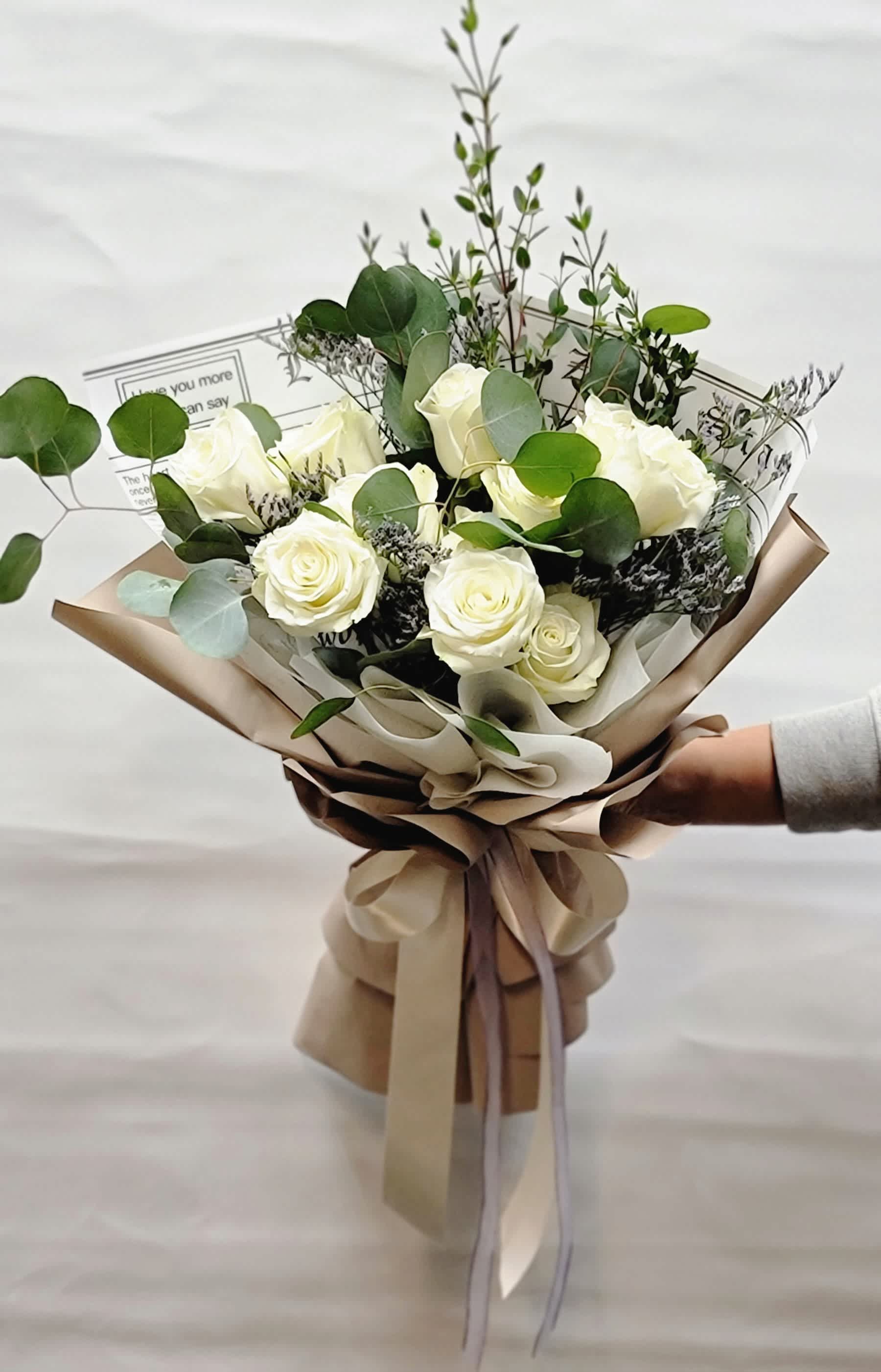 Bouquet of white roses with eucalyptus in tan wrapping