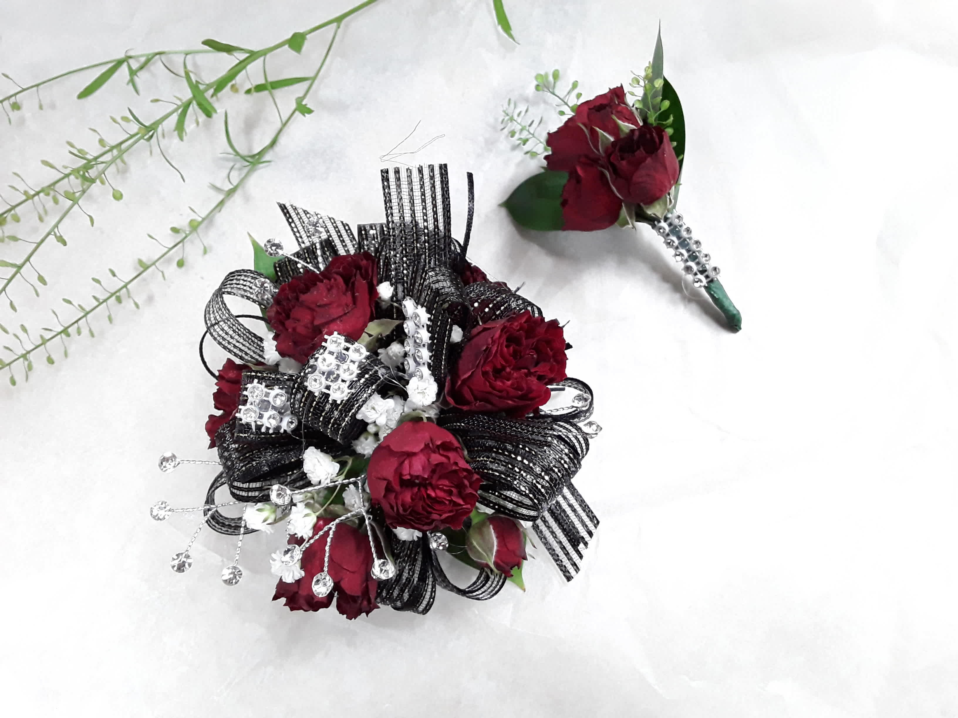 Burgundy floral boutonniere and matching wrist corsage with black ribbon accents