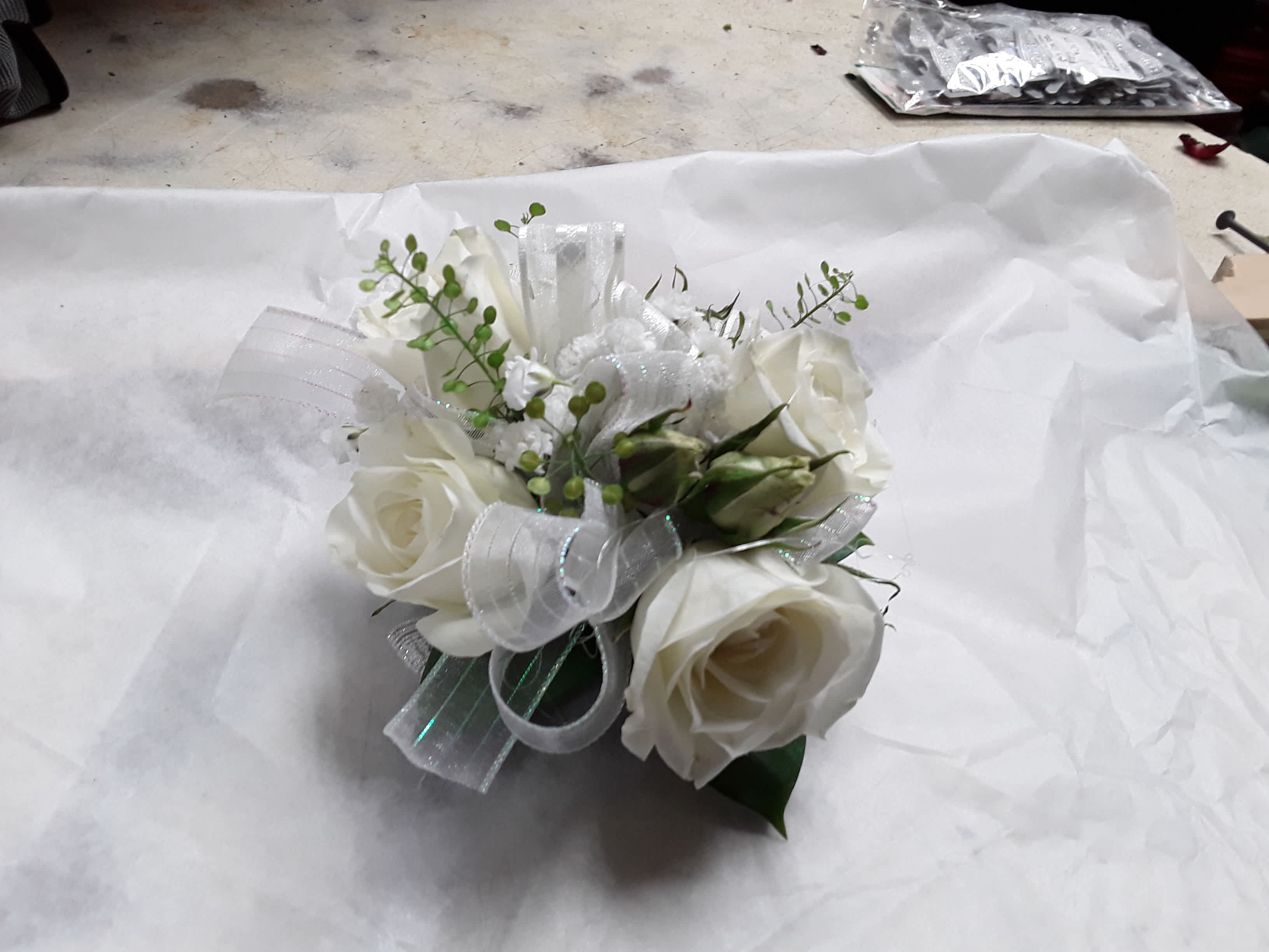 White rose bouquet with silver ribbon and small green accents