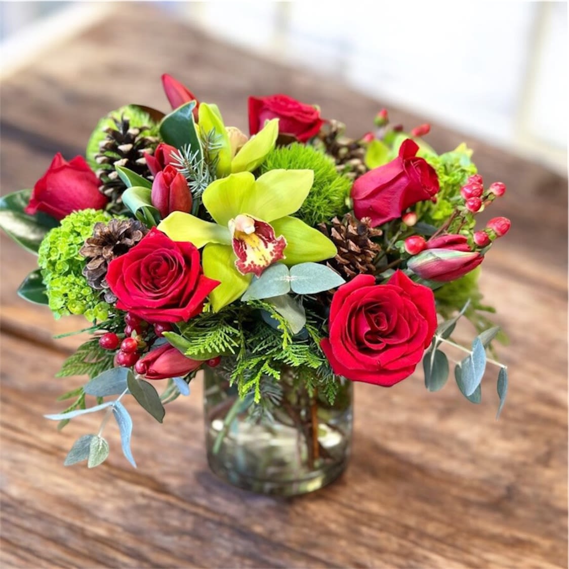 Red roses and green orchids in a glass vase