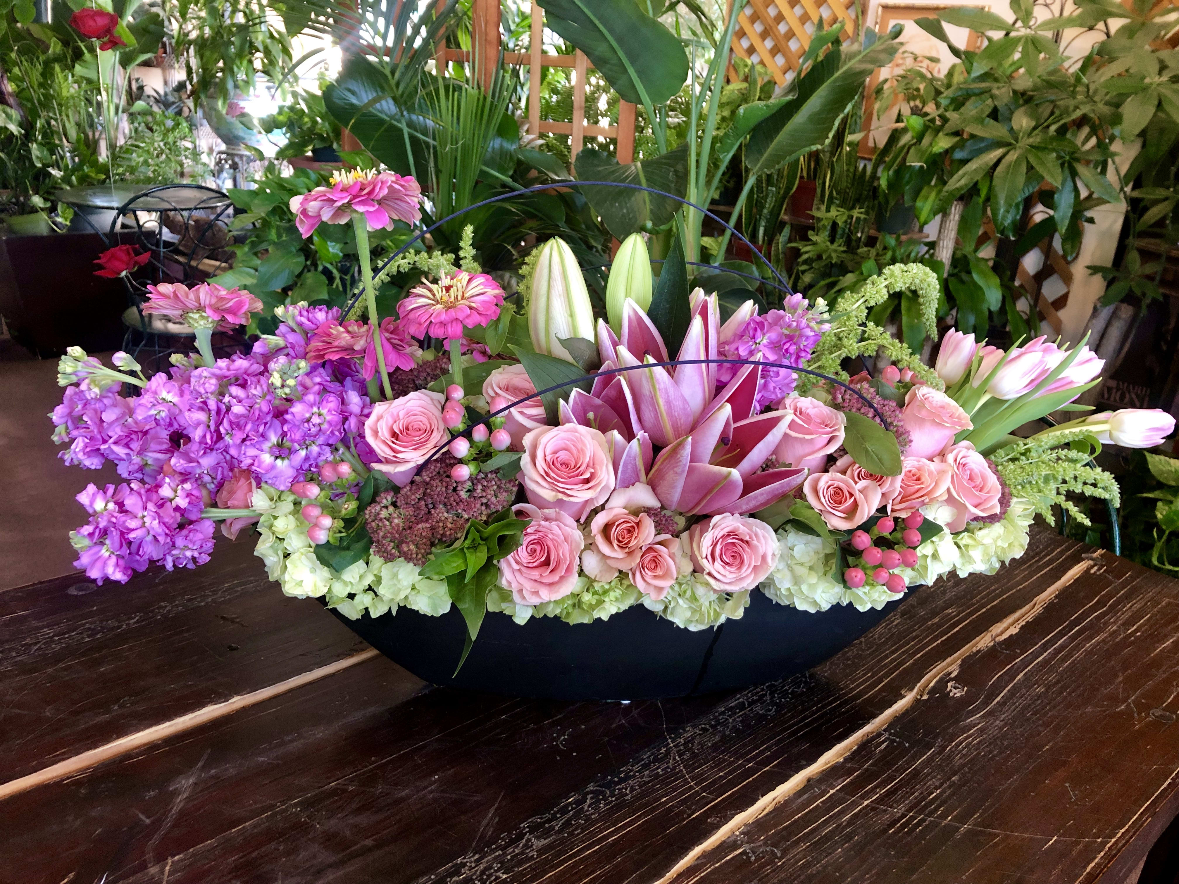 Pink roses and lilies arranged in a low black container