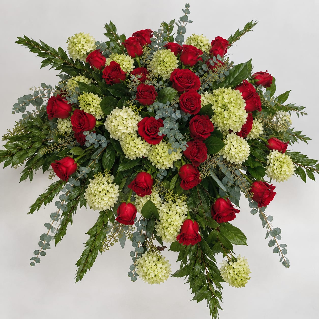 Large arrangement of red roses and pale green hydrangeas with trailing greenery