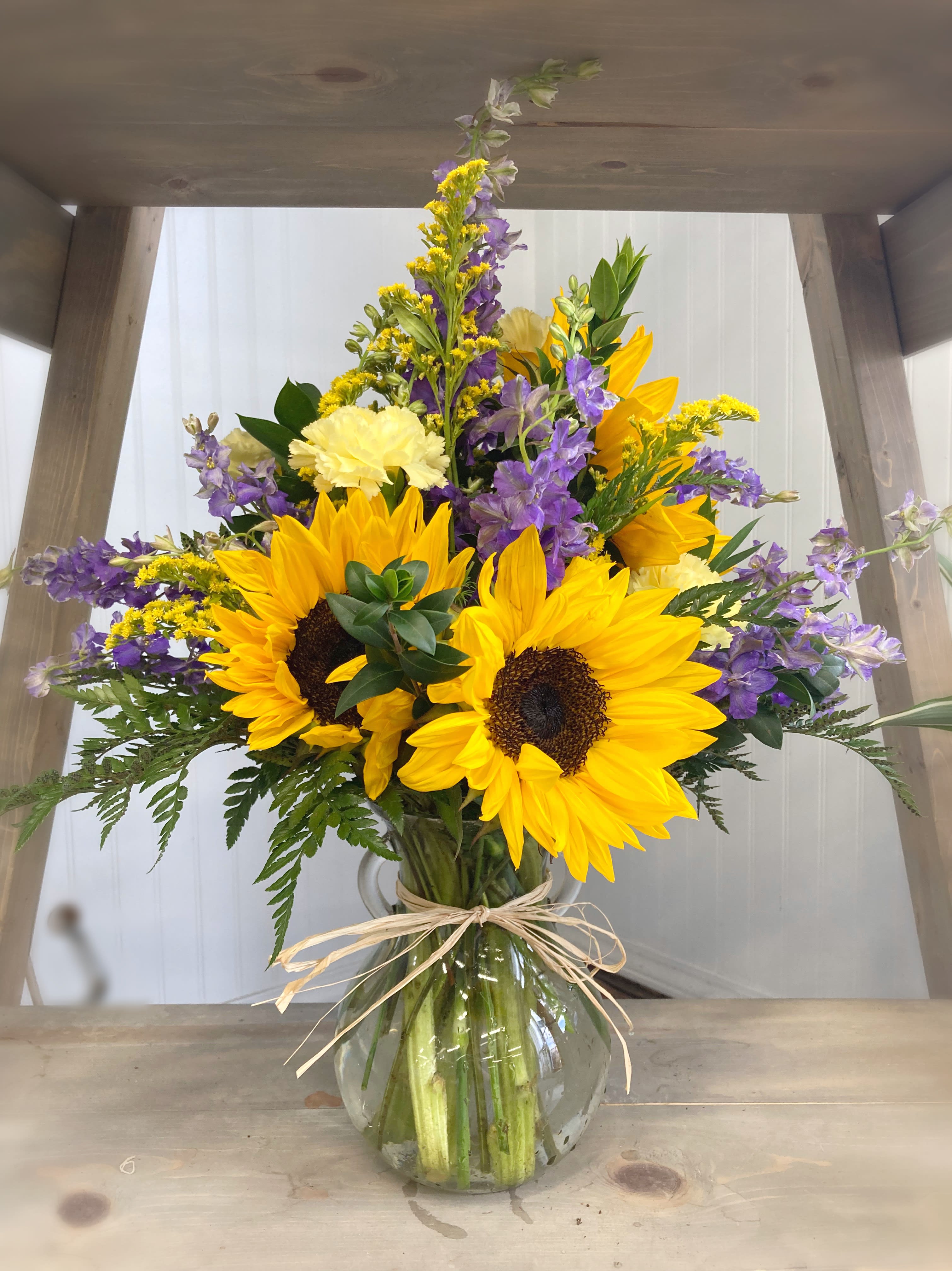 Bouquet of sunflowers, purple flowers, and yellow blooms in a glass vase