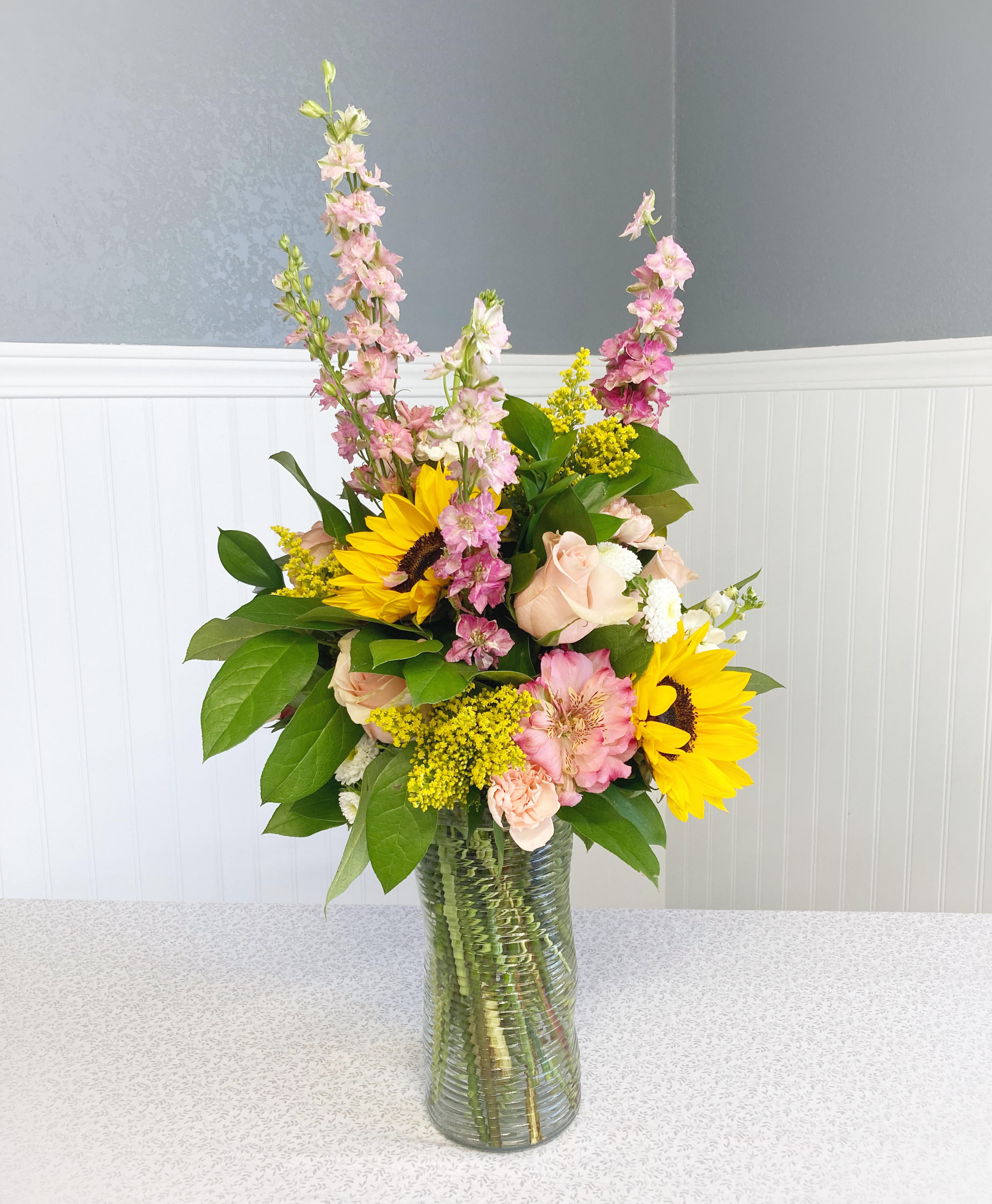 Mixed bouquet with sunflowers, pink blooms, and a glass vase